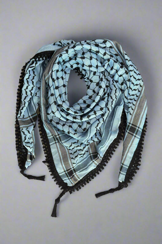 Blue and black patterned scarf with tassels on a wooden surface