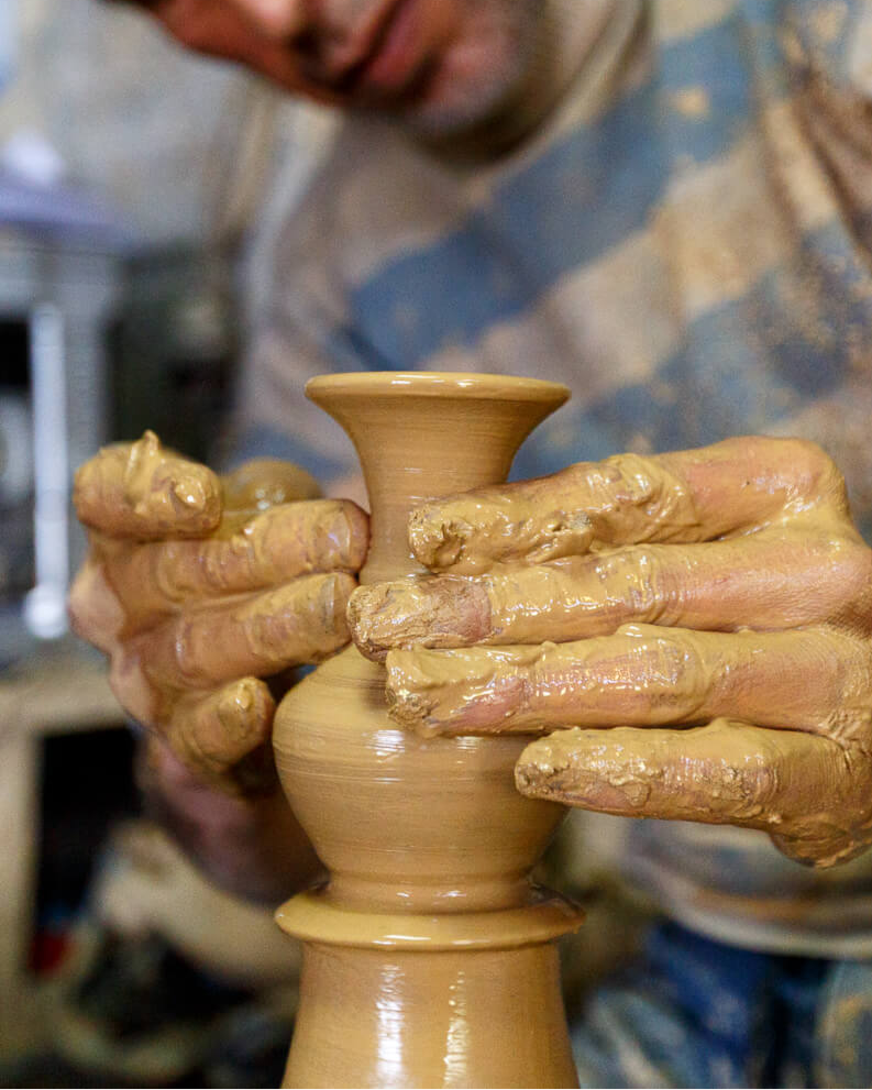 Man working with clay on a potter's wheel in a workshop.