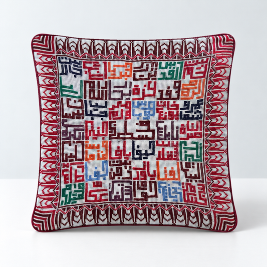Cities of Home hand-stitched cushion with colourful Palestinian city-name embroidery and a red patterned border, standalone studio view